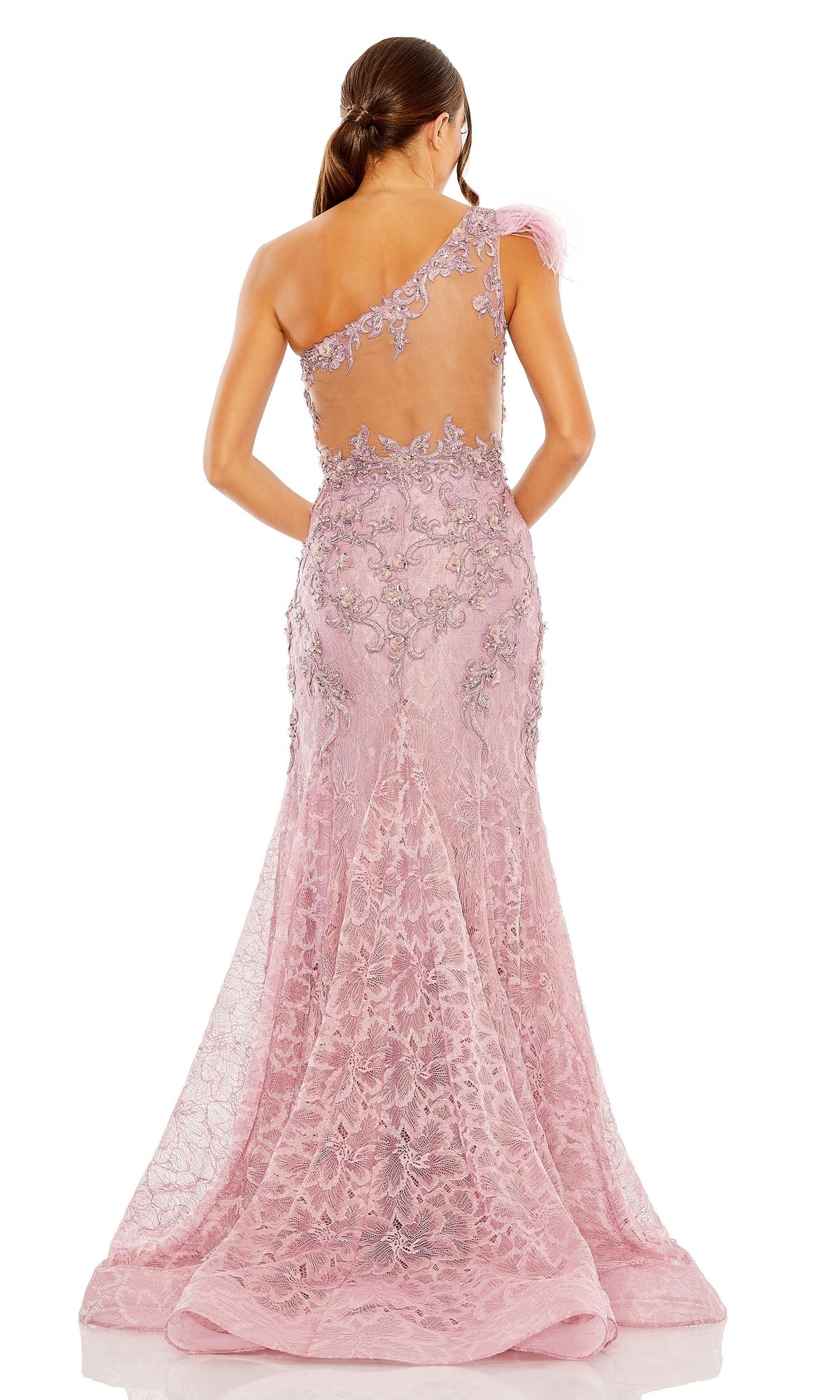 A woman stands with her back to the camera in the Mac Duggal 79264 Feather One-Shoulder Prom Gown, a floor-length pink lace mermaid dress featuring intricate floral details and a sheer back.